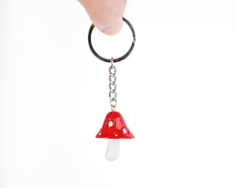 May include: A red and white mushroom keychain with a silver chain and ring.