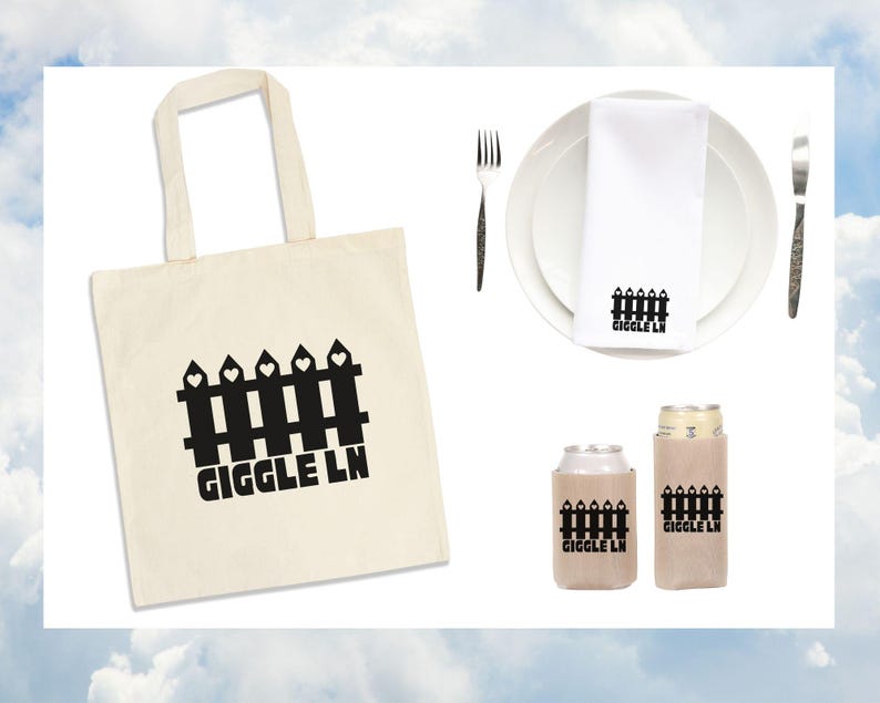 Puede incluir: Colecci&oacute;n de art&iacute;culos con un dise&ntilde;o de valla negra y el texto "GIGGLE LN" en una bolsa de mano color crema, una servilleta blanca sobre un plato y dos enfriadores de latas. Un tenedor y un cuchillo est&aacute;n a cada lado del plato.