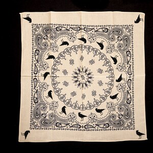 May include: A white bandana with a black paisley pattern and black crow silhouettes. The bandana has a central circle with a floral design.