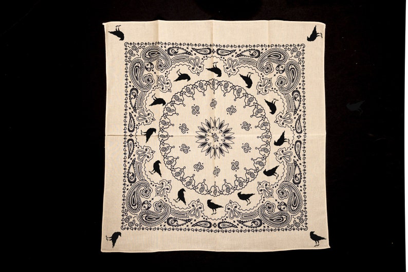 May include: A white bandana with a black paisley pattern and black crow silhouettes. The bandana has a central circle with a floral design.