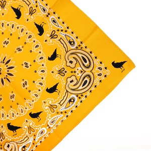 May include: A yellow bandana with a paisley pattern and black crow silhouettes. The bandana has a white border.