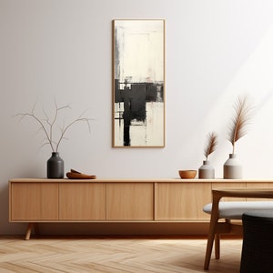 May include: A black and white abstract painting with a wooden frame hangs on a white wall above a light wood cabinet with four doors. The cabinet is sitting on a light wood floor with a herringbone pattern. There are two vases with dried branches on the cabinet.