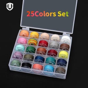 Puede incluir: Una caja organizadora de plástico transparente llena de 25 carretes de hilo de varios colores. El texto "25Colors Set" se muestra en la tapa. Los carretes están dispuestos en una cuadrícula, mostrando una amplia gama de tonos para proyectos de costura o manualidades.