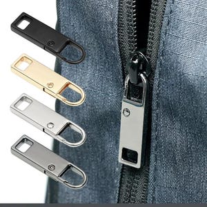 May include: Close-up of a selection of zipper pulls in black, gold, silver, and gunmetal gray. The pulls have a rectangular shape with a loop for easy gripping. A zipper head is also visible.