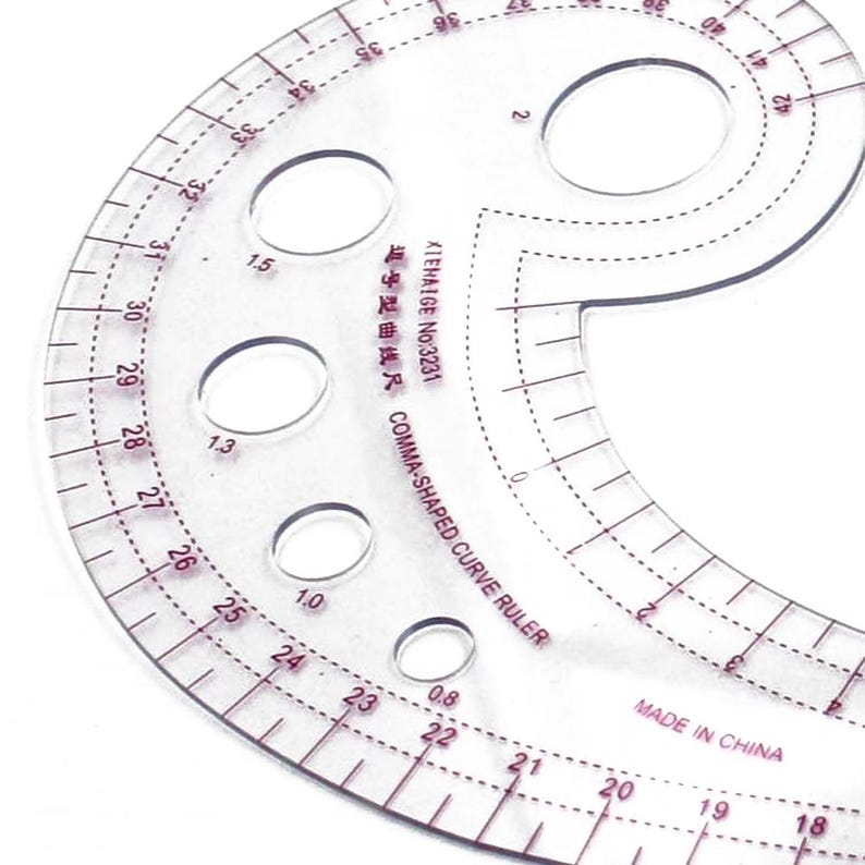 May include: A clear, comma-shaped curve ruler with red markings and several circular cutouts. The ruler has measurements in inches and the text "COMMA-SHAPED CURVE RULER" and "MADE IN CHINA" is visible.
