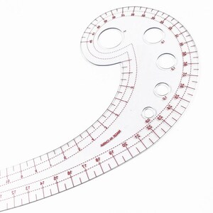 May include: A clear, plastic French curve ruler with red markings and measurements. The ruler has a curved shape with multiple holes and is marked with numbers and lines for precise measurements. The text "MADE IN CHINA" is visible.