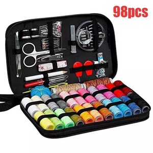 Può includere: Un kit da cucito nero con cerniera contenente 98 pezzi. Il kit include rocchetti di filo di vari colori, forbici, aghi, un ditale, un metro a nastro e altri elementi essenziali per il cucito. Il testo "98pcs" è visibile.