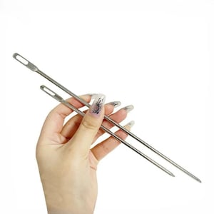 May include: Two long, slender, silver-colored metal needles with elongated eyes at one end. These sewing tools feature a smooth, polished finish and a pointed tip, designed for threading or weaving tasks in various textile and craft projects.