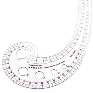 May include: A clear, comma-shaped curve ruler with red markings and circular cutouts. The ruler has measurements in inches and is labeled "KIMATGE No:3231 COMMA-SHAPED CURVE RULER" and "MADE IN CHINA". Ideal for sewing and drafting.