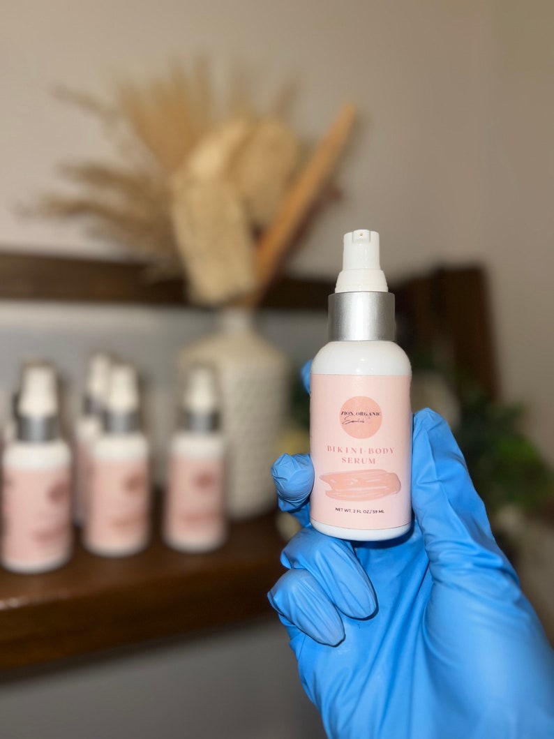 May include: A clear glass bottle with a silver cap and a white label that says "Bikini Body Serum" in pink lettering. The bottle is labeled "Pro Organix" and contains 2 fl oz (59 ml) of serum.