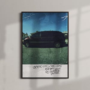 Puede incluir: Un póster enmarcado que muestra una furgoneta oscura estacionada en una carretera de asfalto agrietada bajo un cielo azul. El póster incluye el texto "good kid, m.A.A.d city, a short film by Kendrick Lamar" en estilo manuscrito.