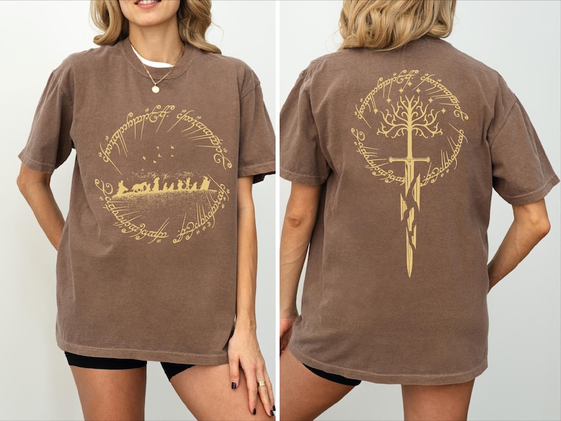 a woman wearing a brown t-shirt with a graphic design featuring a golden tree and a golden sword on the back.