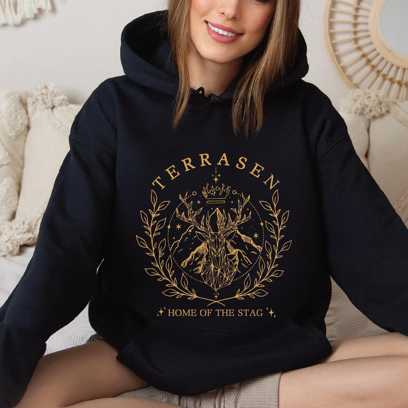 a woman sitting on a couch wearing a black hoodie
