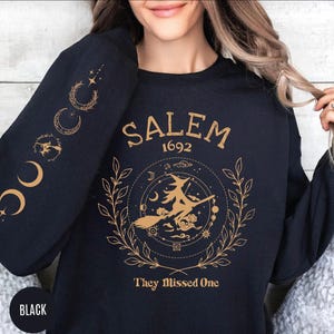 A woman wearing a black sweatshirt with a graphic design on it.