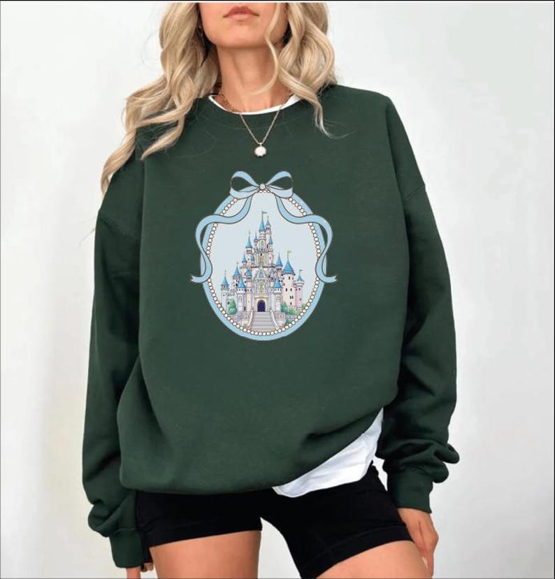 A woman wearing a green sweatshirt with a castle graphic on it.