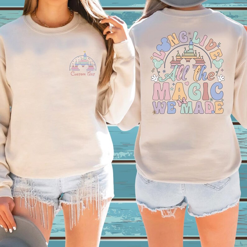 A woman wearing a white sweatshirt with a colorful graphic design on the back, and denim shorts with fringe details.
