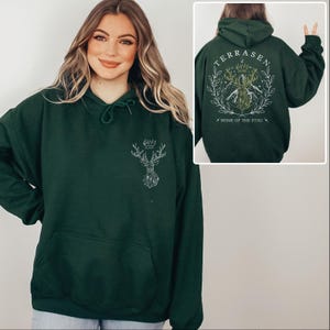 A woman wearing a green hoodie with a design on the back.