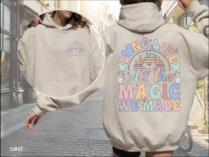 A person wearing a beige hoodie with a colorful graphic design on the back, which appears to be a Disney-themed design.