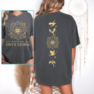 a woman wearing a black shirt with gold designs on it