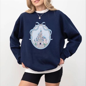 A woman wearing a navy blue sweatshirt with a graphic of a castle on it.
