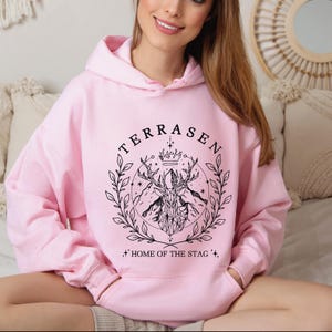 a woman in a pink hoodie sitting on a bed