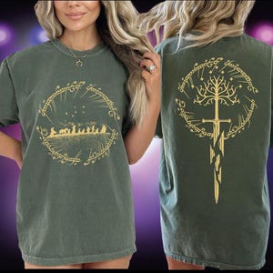 A woman wearing a green t-shirt with a graphic design featuring a tree and a sword.