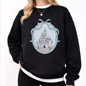 A woman wearing a black sweatshirt with a graphic of a castle on it.