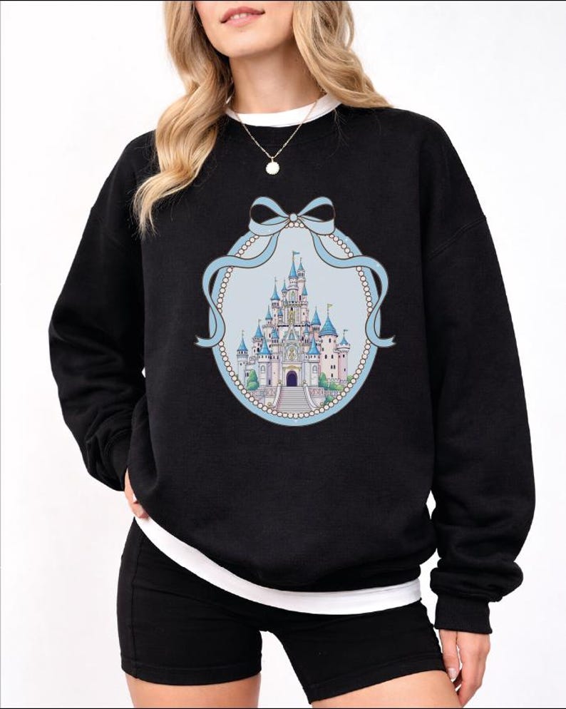 A woman wearing a black sweatshirt with a graphic of a castle on it.