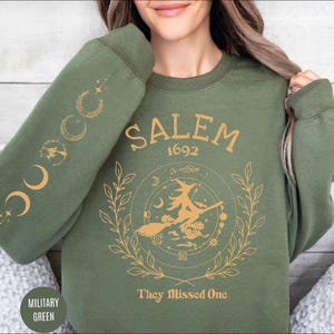 A woman wearing a green sweatshirt with a graphic design on it.