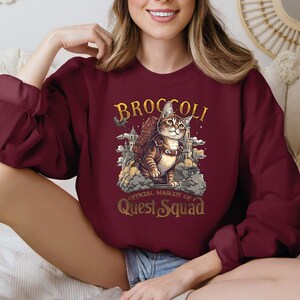 a woman wearing a maroon sweatshirt with a cat on it