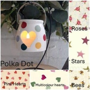 May include: A white ceramic candle holder with a polka dot pattern and a heart-shaped cutout. The holder is on a black metal stand and has a lit candle inside.