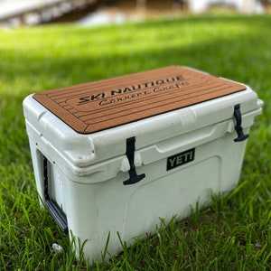 Puede incluir: Nevera blanca Yeti con una tapa de madera marr&oacute;n con el texto "Ski Nautique Connect Crafts".