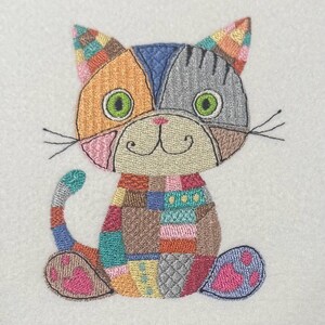 K&ouml;nnte beinhalten: Eine bunte Patchwork-Katze mit gr&uuml;nen Augen und einer rosa Nase. Die Katze sitzt mit ihrem Schwanz um die Beine gewickelt.