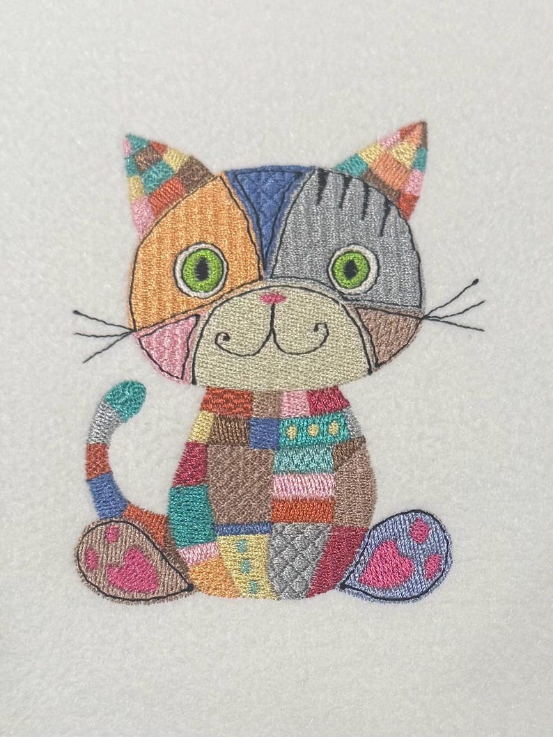 K&ouml;nnte beinhalten: Eine bunte Patchwork-Katze mit gr&uuml;nen Augen und einer rosa Nase. Die Katze sitzt mit ihrem Schwanz um die Beine gewickelt.