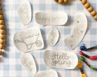 May include: A set of eight iron-on patches featuring spring-themed designs, including flowers, a wheelbarrow, and the text "happy spring" and "hello spring".