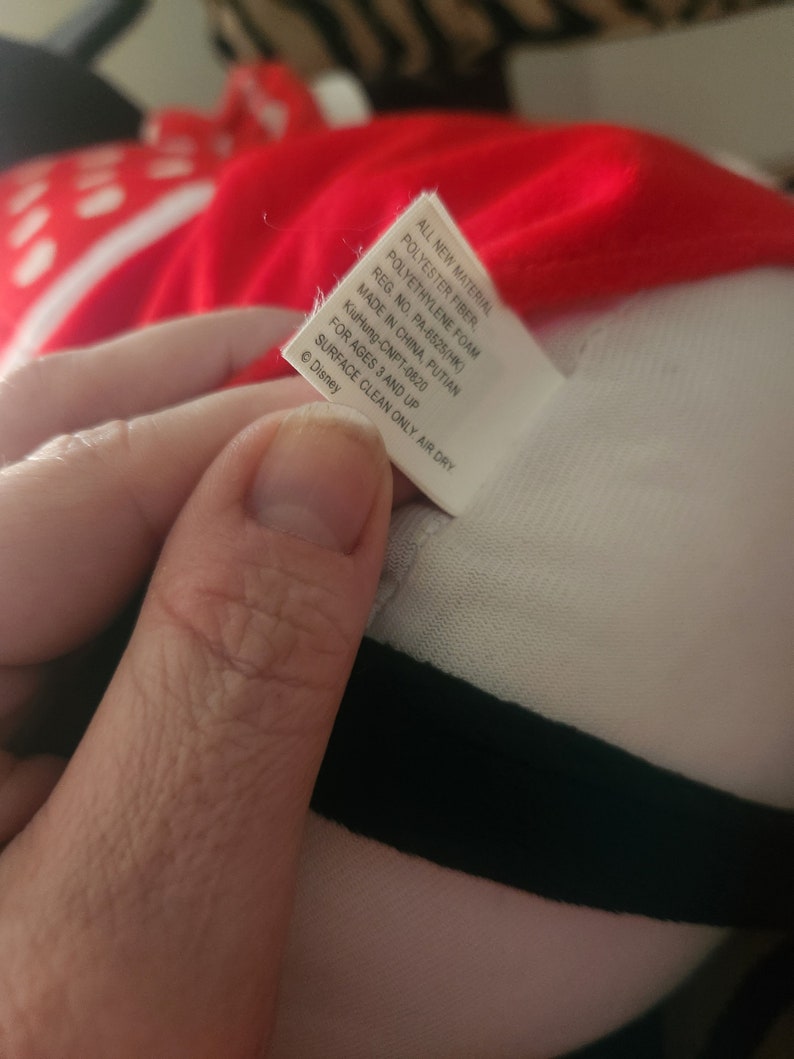 May include: White tag with black text listing the materials used to make the plush toy. The tag reads "All new material Polyester fiber, Polyethylene foam Reg. No. PA-6525(HK) Made in China, Putian KiuHung-CNPT-0820 For ages 3 and up Surface clean only. Air dry &copy; Disney"