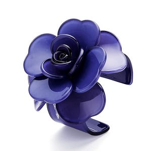 May include: A dark blue, flower-shaped cuff bracelet. The bracelet features a large, stylized rose with multiple petals. The petals are a glossy, translucent blue, with a gradient effect. The bracelet is a statement piece of jewellery.