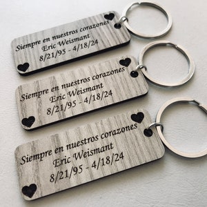 May include: Three wooden keychains with silver key rings. Each keychain has a heart shape and the text "Siempre en nuestros corazones Eric Weismant 8/21/95-4/18/24".