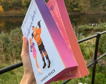 Puede incluir: Dos libros de bolsillo apilados uno encima del otro. El libro de arriba se titula "Icebreaker" y presenta una ilustración colorida de dos personas patinando sobre hielo. El libro de abajo se titula "Love" y tiene una portada con degradado rosa y naranja.