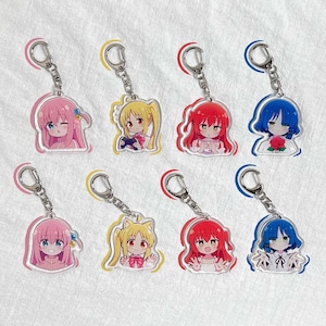 Puede incluir: Conjunto de diez llaveros con personajes de anime con diferentes colores de cabello y atuendos. Los llaveros están hechos de acrílico transparente y tienen anillos de metal plateado.