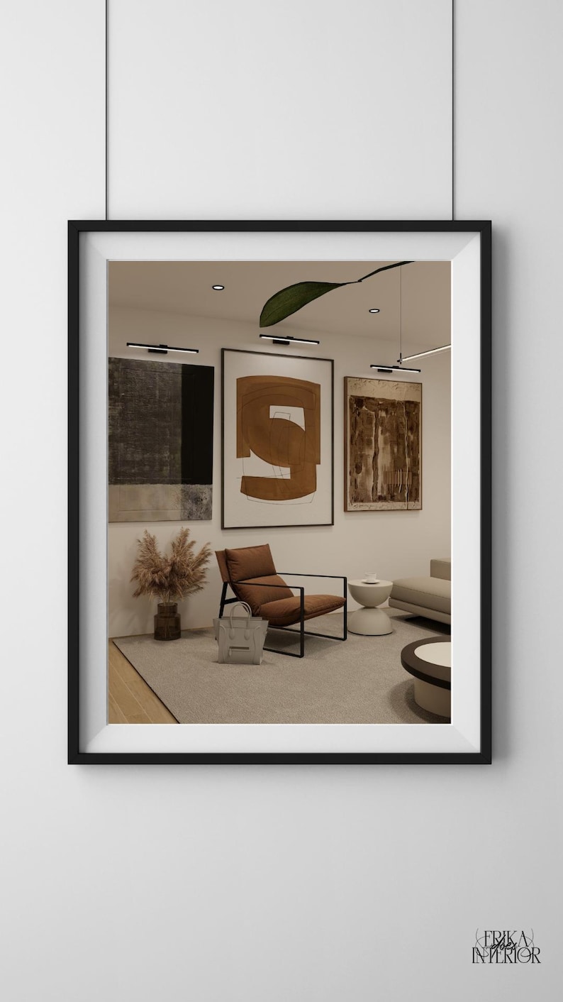 May include: Interior design with framed abstract art in neutral tones. A brown leather armchair with a black frame is positioned in front of the artwork. A grey handbag rests on the floor. The room has a modern, minimalist aesthetic.