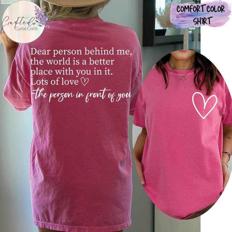 May include: Pink t-shirt with a white heart on the front and the text "Dear person behind me, the world is a better place with you in it. Lots of love - the person in front of you" on the back.