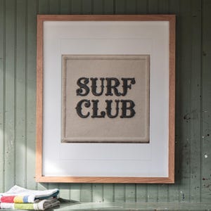 Surf Club Patch print in a Red Oak frame with a white mat, hanging above the cubbies in a mudroom.