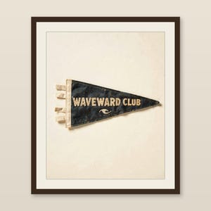 Waveward Club vintage felt surf pennant printable displayed in a warm wood frame on a softly lit neutral wall