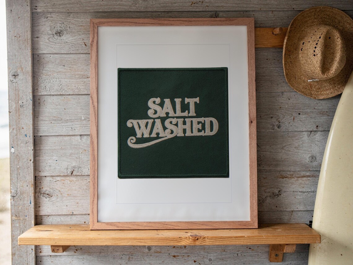 Salt Washed Patch print in a Red Oak frame with a white mat, leaning on the shelf against the wall in a surf shack bedroom.