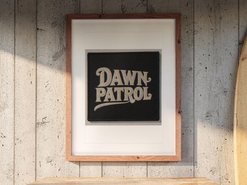 Dawn Patrol Patch print in a Red Oak frame with a white mat, hanging above the dresser in a surf shack bedroom.