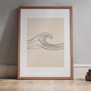 Breaking Wave Line print in a Red Oak frame with a white mat, standing on the floor, leaning back slightly against the wall in a living room floor lean.