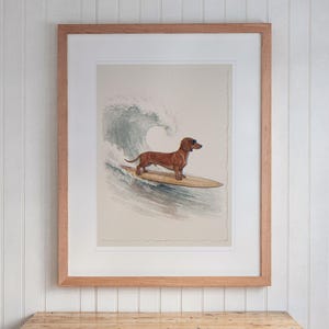 Dachshund Surfing print in a Red Oak frame with a white mat, hanging above the desk in a kids' room.