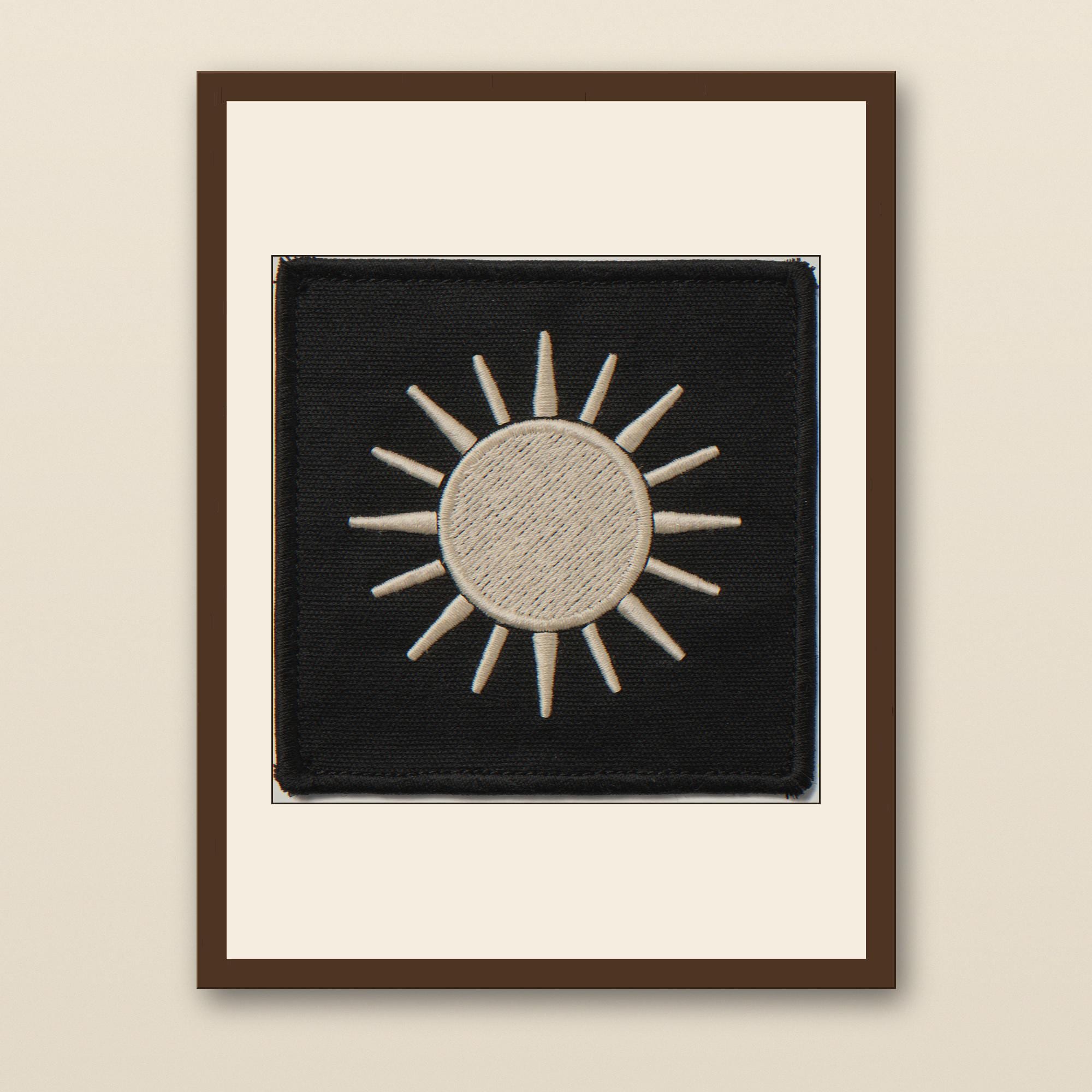 Sun Embroidered Patch Print - walnut framed art print with cream mat on plaster wall