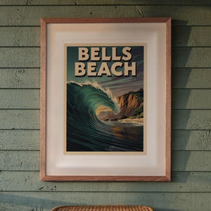 Puede incluir: Un póster enmarcado que muestra una gran ola rompiendo en tonos azul profundo y cerceta, con acantilados escarpados al fondo. El texto "BELLS BEACH" está impreso en letras negritas y claras en la parte superior de la obra.
